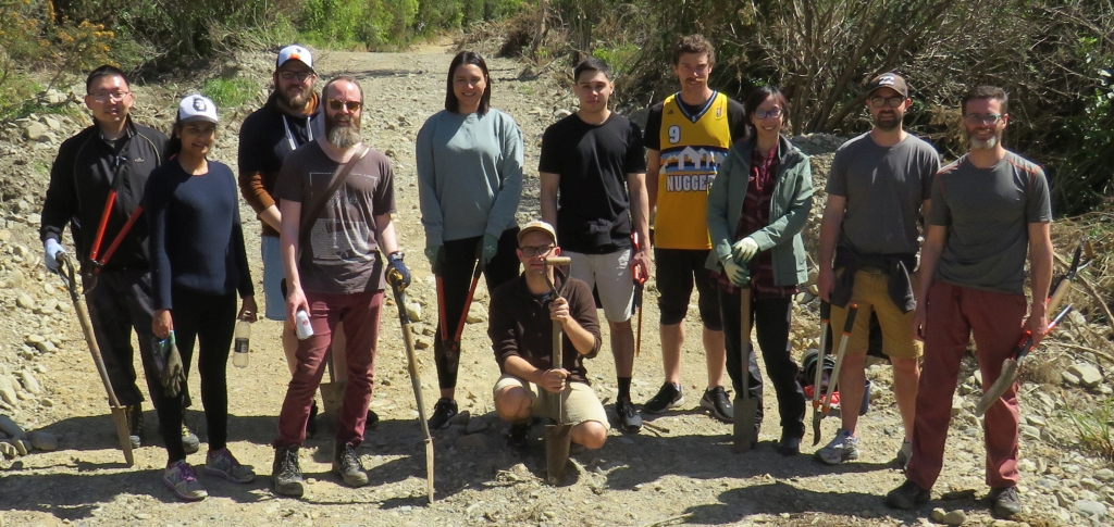 Corporate volunteers from ACC group holding shovels and other tools during their volunteer day down at the wetlands restoration area of the Catchpool Valley.